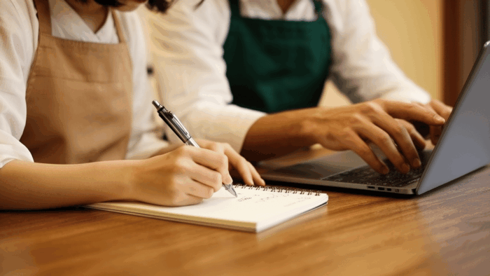 ノートにメモを取りながら経営について話し合う夫婦